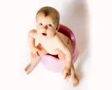 Bambino seduto sul vasino rosa, con espressione sorpresa. Attenzione alla cistite nei bambini.