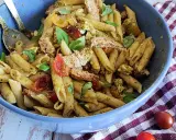 Un plat généreux de penne à la salade pesto, garni de poulet effiloché, tomates cerises et basilic frais. Un délice pour les papilles !