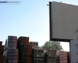 Stosy dachówek i materiałów budowlanych pod pustym billboardem. Reklama na budynku inaczej, czekająca na nowe hasło.