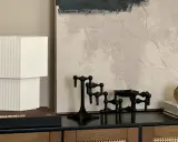 En stilren stilleben inredning med en vit lampa, svarta ljusstakar och en bok med texten "Dior".