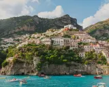 Positano, un gioiello da scoprire, perfetto per chi cerca cosa vedere a Napoli in un giorno. Case colorate aggrappate alla scogliera, mare azzurro e barche.