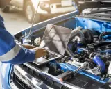 Mechanik z laptopem optymalizuje pracę silnika, przygotowując go do chip tuningu.