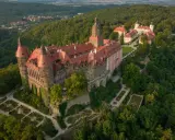 Zamek Książ w górach wałbrzyskich, otoczony bujną zielenią, z malowniczymi ogrodami i wieżami.