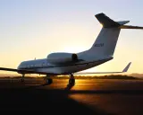 Ein weißer Privatjet steht im Sonnenuntergang auf dem Rollfeld. Verschiedene privatjets modelle sind auf dem Markt, aber dieser hier strahlt Luxus aus.