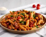 Penne z sosem pomidorowym, kawałkami suszonych pomidorów i świeżą bazylią. Idealne makaron z pomidorkami koktajlowymi na szybki obiad.
