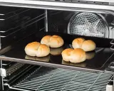 Cinq petits pains dorés sur une plaque de cuisson dans un four. C'est une bonne question : qu'est-ce qu'un lèchefrite ? C'est cette plaque !