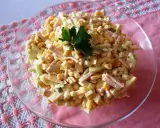 Pyszna sałatka z szynką, kukurydzą i serem, udekorowana natką pietruszki. Idealna na każdą okazję.