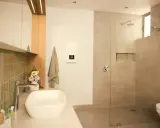 Modernes Bad mit Dusche und Waschbecken. Ein Durchlauferhitzer hängt an der Wand, der für warmes Wasser sorgt, auch wenn man ihn an 230V anschließen möchte.