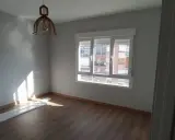 Habitación con suelo de madera, paredes grises y ventana. El sol ilumina la estancia, sugiriendo un buen **precio medio reforma integral**.