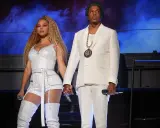Beyoncé i Jay-Z, symbol sukcesu i majątku, na scenie w błyszczących strojach.