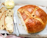 Ein goldbraunes Osterbrot mit Rosinen, aufgeschnitten und mit Butter bestrichen. Perfekt für ein Osterbrot Rezept.