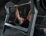 Mann beim Bankdrücken, ein wichtiger Teil seines Powerlifting Trainingsplans.