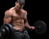 Ein muskulöser Mann mit Tattoos hebt eine Langhantel. Sein Sixpack ist deutlich sichtbar, ein Zeichen für seinen Powerlifting Trainingsplan.