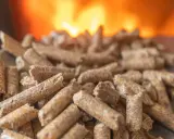 Granulés de bois prêts pour l'installation d'un poêle à granule, avec des flammes chaudes en arrière-plan.
