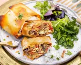 Deux bricks au thon croustillantes, garnies d'une farce savoureuse, servies avec une salade fraîche et une sauce crémeuse.