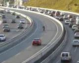 Tráfico intenso en una autopista con varios carriles. Coches, furgonetas y una moto forman la **circulación vao** en un día soleado.