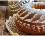 Ciambellone allo yogurt soffice e profumato, cosparso di zucchero a velo su un centrino di pizzo, pronto per essere gustato.