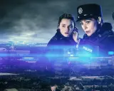 Poliser i uniform över en stadssiluett, upplyst av blåa ljus.