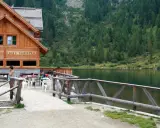 Rifugio sul lago nambino, con tavoli all'aperto e un bosco di conifere sullo sfondo.