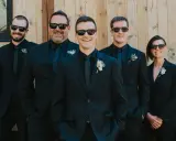 Groomsmen in matching black suits and sunglasses, showcasing stylish black suit ideas for a wedding party.