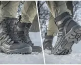 Czarne buty bushcraft na śniegu, z grubą podeszwą i sznurowaniem, gotowe na zimowe wyzwania.