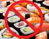 Rotes Verbotsschild über Sushi und Maki-Rollen. Achtung: verbotene Lebensmittel Schwangerschaft.