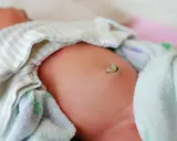 Delikatny brzuszek noworodka z widocznym pępowiną, która zaczyna zasychać. Uważne obserwowanie go pomoże uniknąć zapalenia pępka u noworodka.