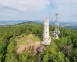 Wieża widokowa i maszt telekomunikacyjny na szczycie porośniętym lasem w Górach Sowich. Wokół miejsca do odpoczynku.