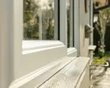 Biały parapet z konglomeratu na zewnątrz, z widokiem na zielony ogród.