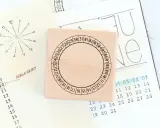 Holzstempel mit Kreis und Zahlen für den koptischen Kalender, daneben eine handgezeichnete Monatsübersicht.
