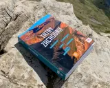 Przewodnik "Tatry Zachodnie" leży na skale. Na okładce widnieje m.in. Dolina Kościeliska.