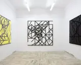 Galeria sztuki z trzema obrazami: żółtym, czarno-białym i czarnym, wszystkie w stylu abstrakcji w malarstwie, z geometrycznymi wzorami.