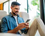 Hombre sonriente usando su móvil para bbva abrir cuenta.