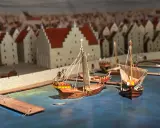 Modell av medeltida hamn i Visby. Skepp ligger vid kajen framför stadens karaktäristiska hus. En glimt av Visby historia.
