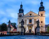 Imponująca bazylika na Kalwarii Zebrzydowskiej, z rzeźbami świętych przed bramą i wieżami w niebo.