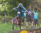 Troy Brosnan springt mit seinem Downhill-Bike über eine Holzrampe, bereit für den nächsten Sprung.