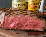 Saftiges, medium-gebratenes Steak mit Grillstreifen, daneben Flaschen für die perfekte Steak Marinade.