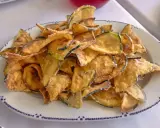 Montón de berenjenas fritas crujientes y doradas en un plato blanco con borde azul. ¡Un aperitivo delicioso!