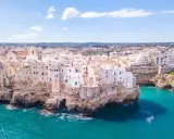 Vista aerea di Polignano a Mare, una delle più belle città da visitare in Puglia, con case bianche aggrappate alle scogliere a picco sul mare turchese.
