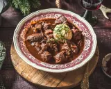 Ein festliches Hirschgulasch, wie es ein Sternekoch zubereiten würde, serviert mit Klößen und Preiselbeeren.
