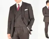 A man in a dark pinstripe suit, white shirt, and red patterned tie. He's adjusting his cuff, ready for a formal event.