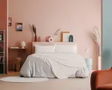 Camera da letto con pareti rosa e turchesi, un letto accogliente e decorazioni che evocano i colori della cromoterapia.