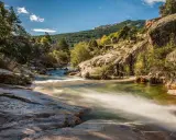 Río serpenteante entre rocas y vegetación, ideal para excursiones cerca de Madrid. Un paisaje natural de ensueño.