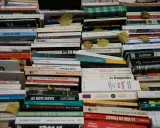 Une pile de livres anciens, certains jaunis par le temps. On peut y lire des titres comme "La nuit à Paris" ou "Le savoir-vivre libertin". L'image invite à interagir avec la conjugaison des mots et des histoires.