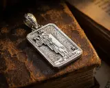 Srebrny wisiorek z motywem pustelnika tarot, leżący na starych księgach.