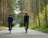 Para jazda na rowerze: kask, okulary, długie rękawy i spodnie. Dwóch rowerzystów w lesie.
