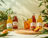 Butelki kombuchy i szklanka z napojem, otoczone owocami i zielenią. Odkryj kombucha właściwości dla zdrowia.