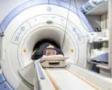 Mężczyzna leży w aparacie do rezonansu magnetycznego, przygotowując się do badania. Jego głowa jest uniesiona na poduszce, a uszy chronią słuchawki. To badanie może pomóc zrozumieć rezonans morficzny.
