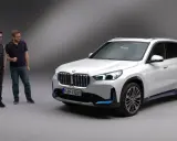 Dwóch mężczyzn stoi obok białego BMW iX1.