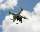 Weiße Drohne mit roten und grünen Lichtern fliegt im blauen Himmel mit Wolken. Beachten Sie die Drohnen Richtlinien für sicheren Flug.